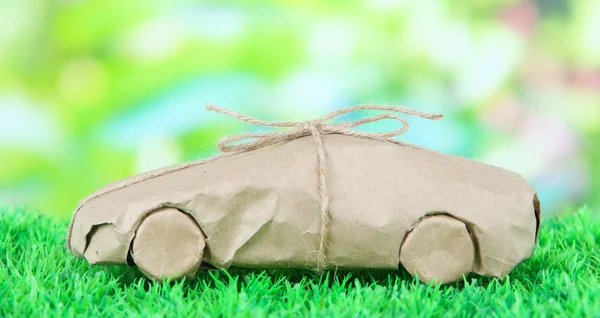 Car wrapped in brown kraft paper, on green grass, on nature background — Stock Photo, Image