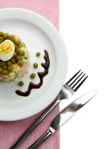 Salada tradicional russa Olivier em prato branco, em guardanapo de cor, isolado em branco — Fotografia de Stock
