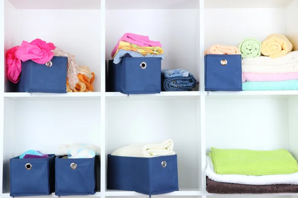 Синие текстильные коробки с игрушками и одеждой на белых полках — стоковое фото