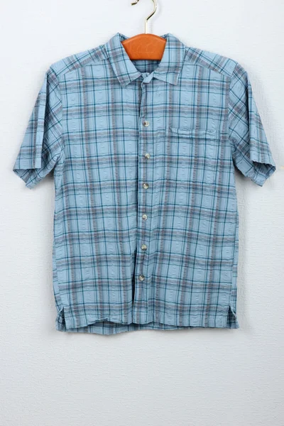 Camisa masculina en percha de madera sobre fondo de pared —  Fotos de Stock