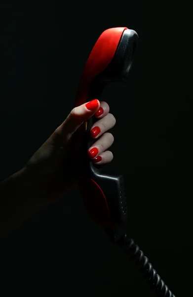 Receiver in female hand,on dark background — Stock Photo, Image