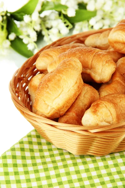 Tasty croissants in wicker basket on table on white background Stock Image