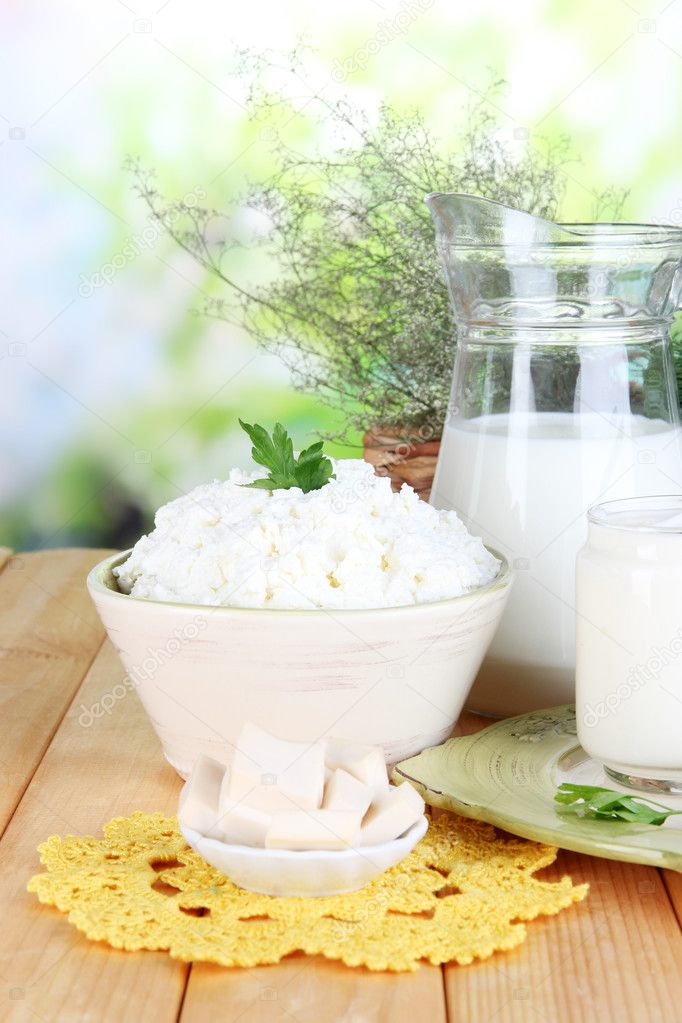 Fresh dairy products with greens on wooden table on natural background