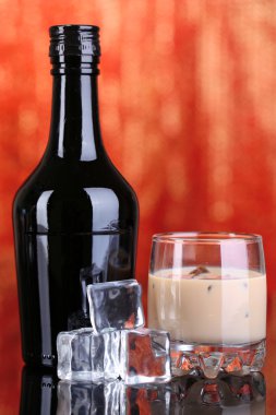 Baileys liqueur in bottle and glass on red background clipart
