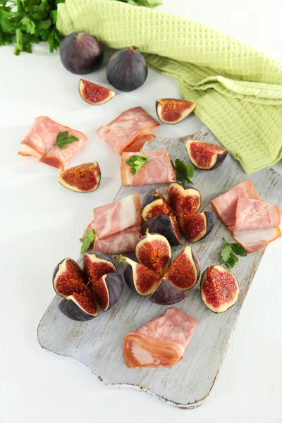 Smakelijke vijgen met ham op witte houten tafel — Stockfoto