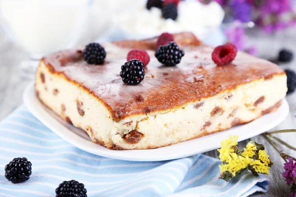 Cheese casserole with raisins on plate on napkin on wooden table close-up — Stock Photo, Image