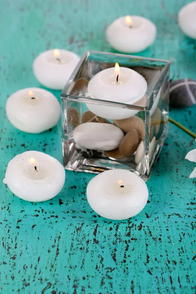 Jarrón decorativo con velas, agua y piedras sobre mesa de madera —  Fotos de Stock