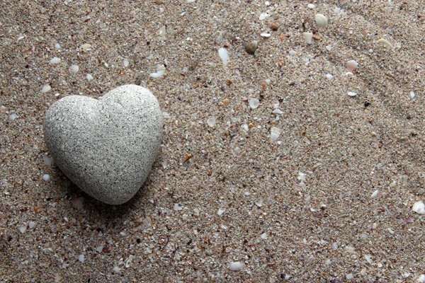 Grey stone in shape of heart, on sand background — Stock Photo, Image