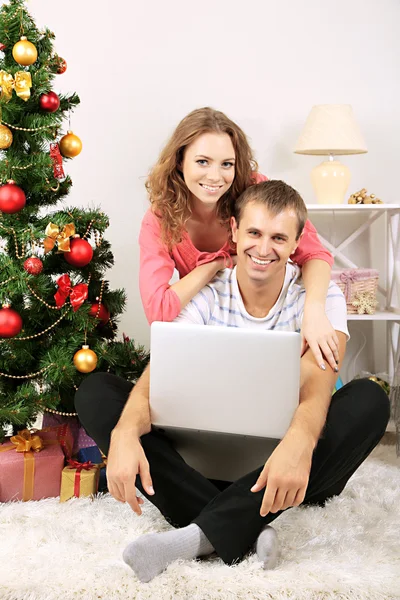 Glückliches junges Paar in der Nähe von Weihnachtsbaum zu Hause — Stockfoto