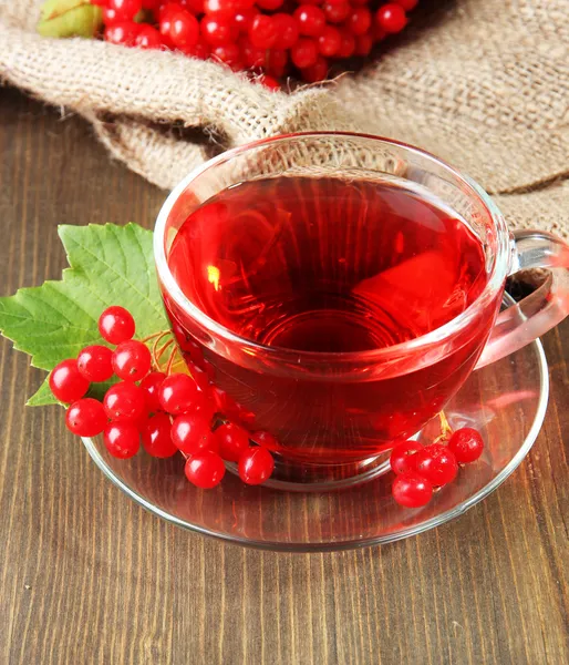 Bodegón con té de viburnum en servilleta de tela de saco, sobre fondo de madera — Stok fotoğraf