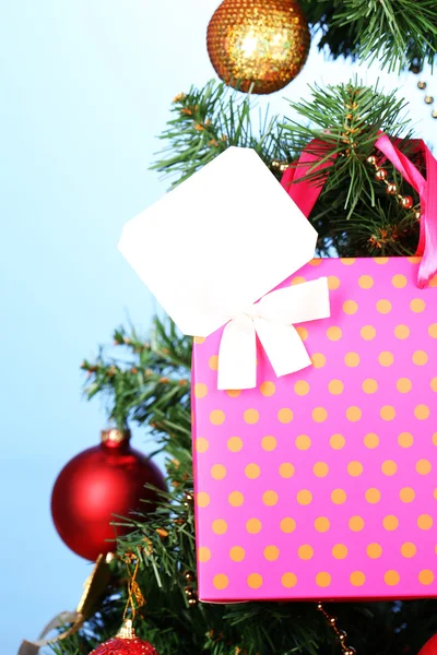 Regalo en el árbol de Navidad sobre fondo de color — Foto de Stock