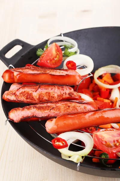 Deliciosas salchichas con verduras en wok sobre mesa de madera de cerca —  Fotos de Stock