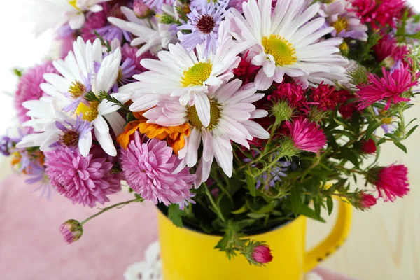 Kwiaty w kubek na serwetki na stół drewniany — Zdjęcie stockowe