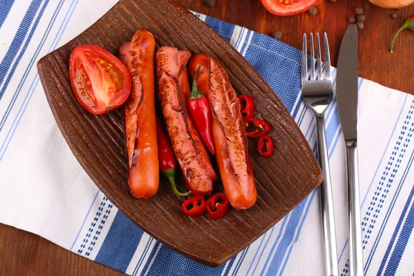 Salsichas deliciosas com legumes no prato na mesa de madeira close-up — Fotografia de Stock