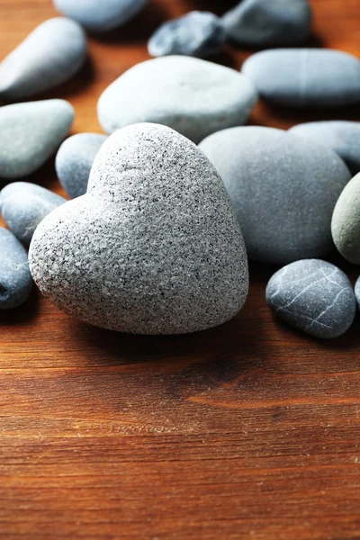 Piedra gris en forma de corazón, sobre fondo de madera — Foto de Stock