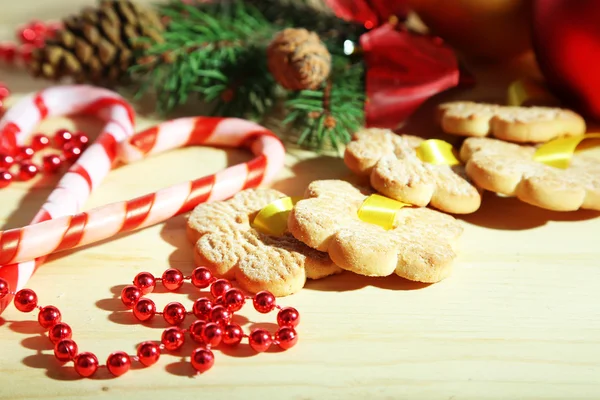 Cookies on ribbons with Christmas decorations on wooden table — Stock Photo, Image