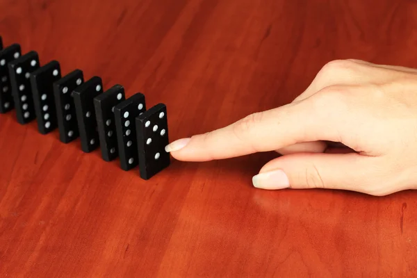 Mano spingendo domino su sfondo di legno — Foto Stock