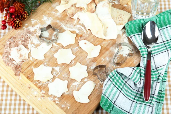 Dokonywanie ciasteczka świąteczne na desce na tle Obrus — Zdjęcie stockowe