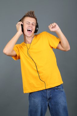 yakışıklı genç adam gri arka planda müzik dinlemek