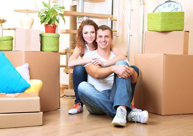 Young couple sitting in new house on staircase background clipart