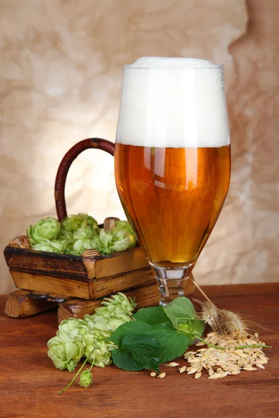 Glass of beer and hops, on wooden table — Stock Photo, Image