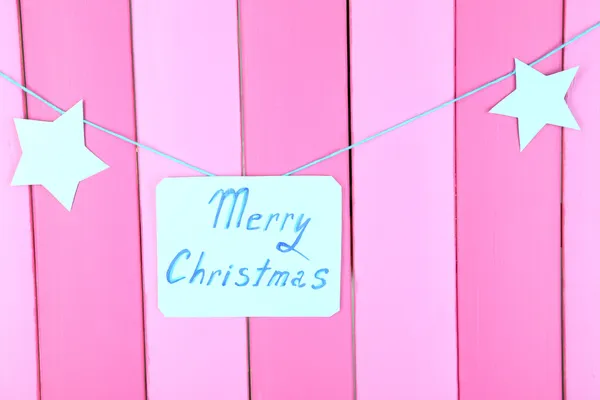 Bord met woorden vrolijk kerstfeest op roze houten tafel achtergrond close-up — Stockfoto