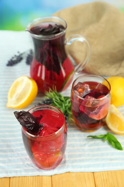 Limonata di basilico rosso in brocca e vetro, su tavolo di legno, su sfondo brillante — Foto Stock