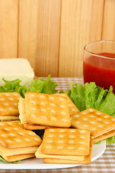 Ahşap zemin üzerinde masa örtüsü üzerinde peynir ve domates suyu ile sandviç kraker — Stok fotoğraf