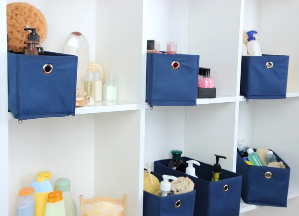 Blaue Textilboxen mit Kosmetikprodukten für die Körperpflege in weißen Regalen — Stockfoto