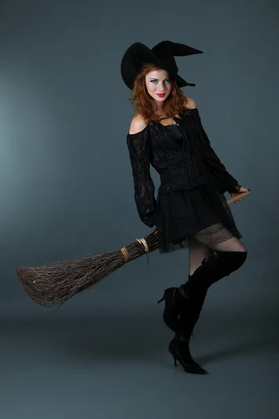 Хэллоуинская ведьма с метлой на сером фоне — стоковое фото