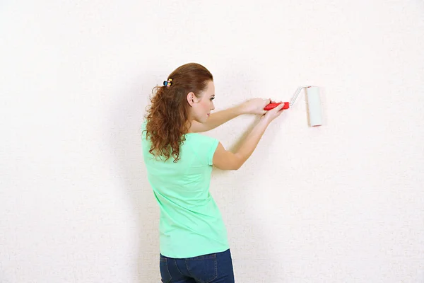 Jovem mulher pinta parede em novo apartamento — Fotografia de Stock