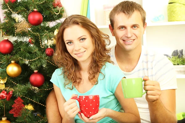 Glückliches junges Paar in der Nähe von Weihnachtsbaum zu Hause — Stockfoto