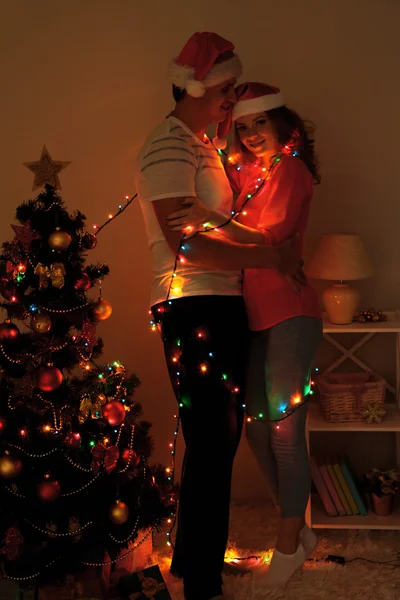Feliz pareja joven cerca del árbol de Navidad en casa —  Fotos de Stock