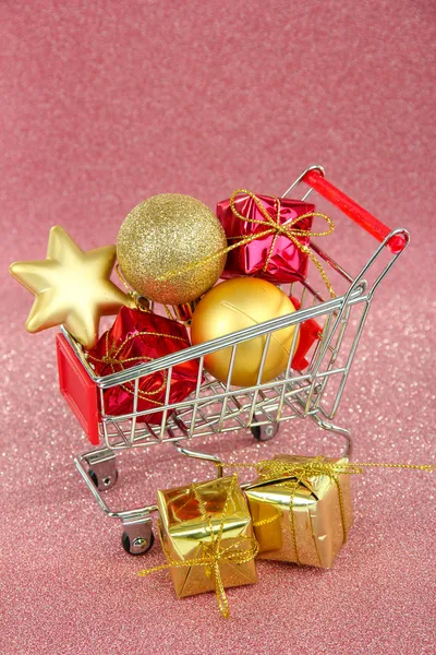 Regalos de Navidad en el carrito de la compra, sobre fondo rosa brillante — Foto de Stock