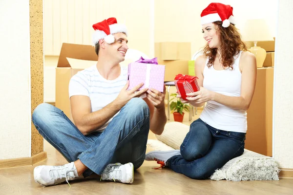 Casal jovem com caixas em nova casa celebrando o Ano Novo — Fotografia de Stock