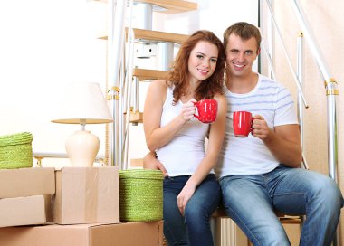 Young couple sitting on stairs in new house clipart