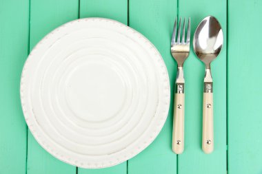 Plate and cutlery on wooden table close-up