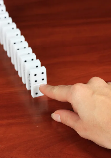 Mano spingendo domino su sfondo di legno — Foto Stock