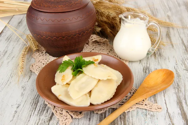 Gnocchi gustosi con cipolla fritta su piatto marrone, su fondo di legno — Foto Stock