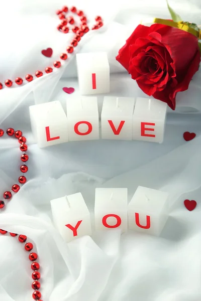 Candles with printed sign I LOVE YOU, on white fabric background — стоковое фото