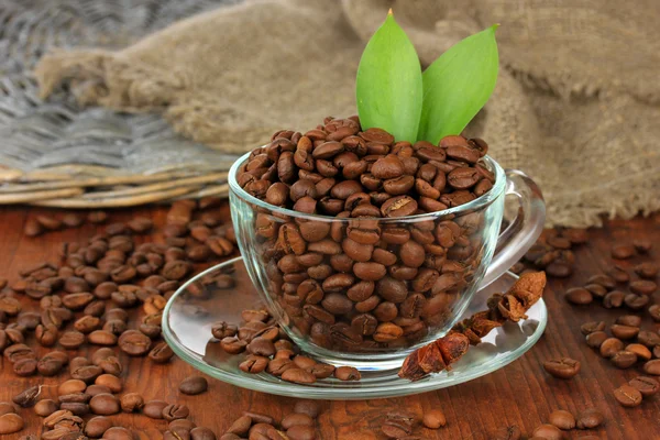 Kaffebönor i cup på trä bakgrund — Stockfoto