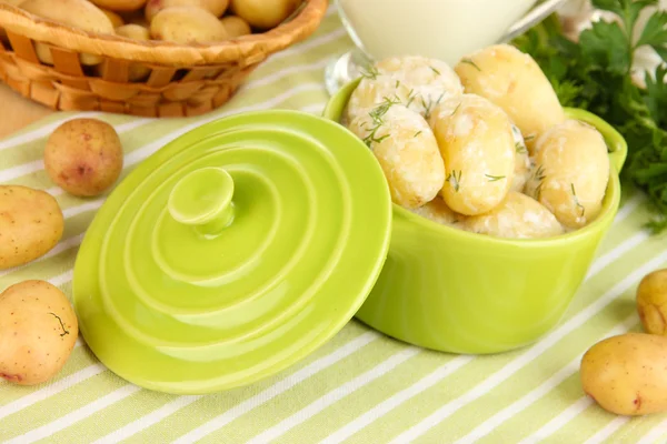 Inschrijving van jonge aardappelen met zure room en kruiden in pan op houten tafel close-up — Stockfoto