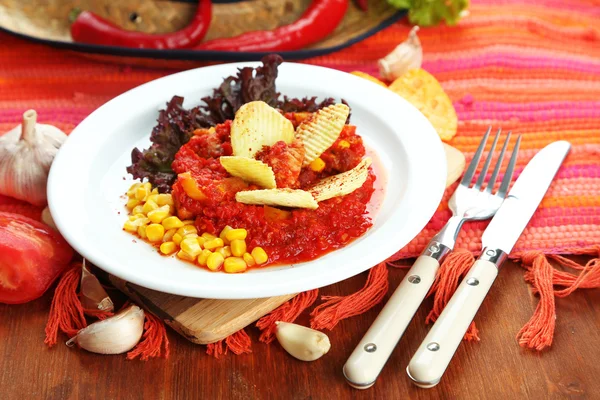 Chili Corn Carne - traditionel mexicansk mad, på hvid tallerken, på serviet, på træbaggrund - Stock-foto