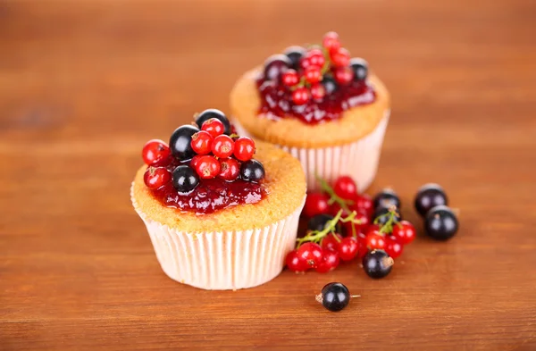 Tasty muffins with berries on wooden background — Stok fotoğraf