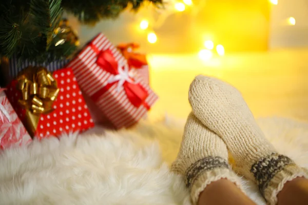 Nohy v ponožkách u vánočního stromu na carped — Stock fotografie