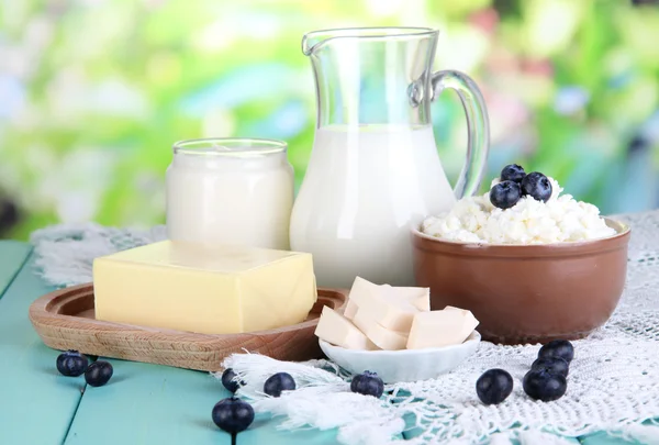 Färska mjölkprodukter med blåbär på träbord på naturliga bakgrund — Stockfoto