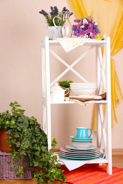 Krásné bílé police s nádobí a dekoracemi na zeď na barvu pozadí — Stock fotografie
