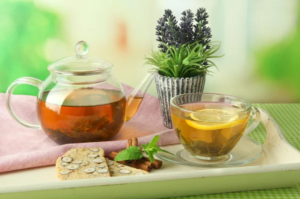 Cup and teapot of green tea with cookies on table on bright background — Stock Photo, Image