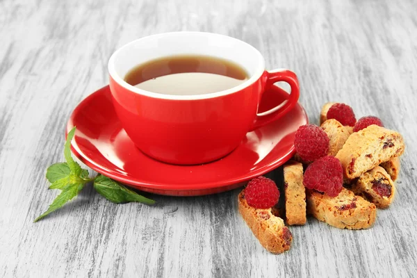 Чашка чая с печеньем и малиной на столе крупным планом — стоковое фото