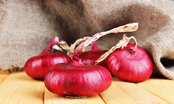 Cebolas vermelhas frescas na mesa de madeira — Fotografia de Stock